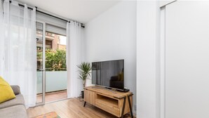 Un salon moderne avec un meuble TV en bois, un canapé gris et un tapis coloré.