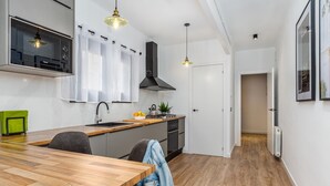 Une cuisine moderne avec une table à manger en bois, un four encastré et des luminaires suspendus.