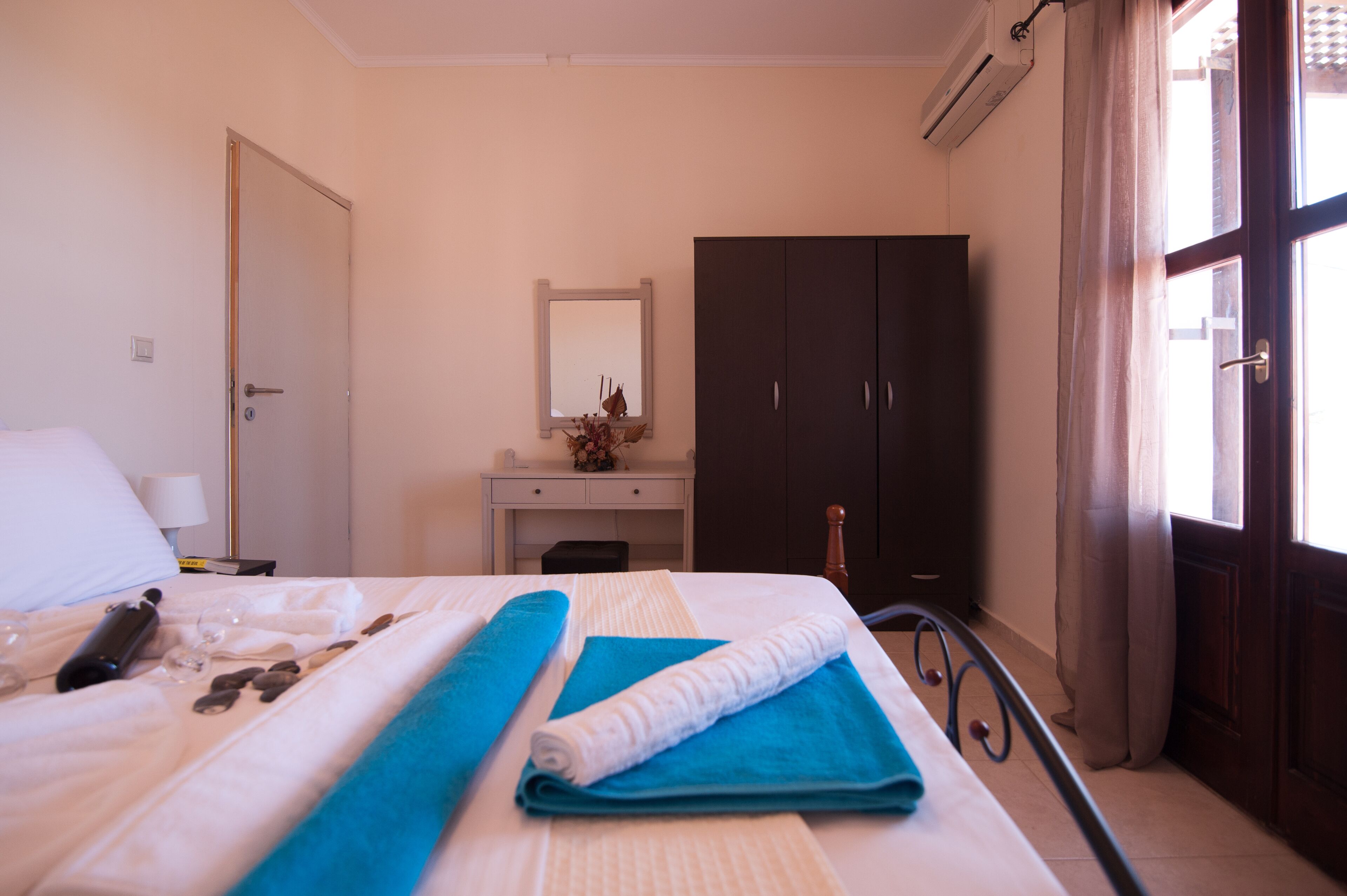 A hotel room with a bed, a desk, a wardrobe, and a window with curtains.