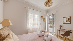 A bedroom with a bed, a desk, a chair, and a view of the outdoors. - Poseidonia Syros Cozy House (Poseidonia)