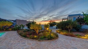 A courtyard with stone pathways, a pool, and various plants. - Poseidonia Syros Cozy House (Poseidonia)