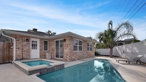A residential property with a swimming pool, a brick house, and a palm tree. - Surf's Up -  Private Heated Pool and Hot Tub - Walk to Beach (St. Augustine)