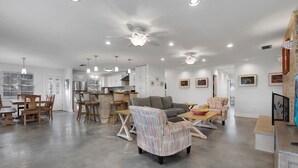 A spacious living area with a kitchen, dining area, and seating with a large window. - Surf's Up -  Private Heated Pool and Hot Tub - Walk to Beach (St. Augustine)
