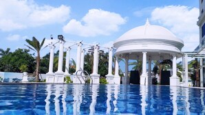 A swimming pool with a gazebo, palm trees, and a modern building in the background. - Grand View Palace Ha Long Hotel (Hong Gai)