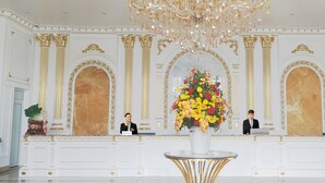 A reception area with a chandelier, a receptionist, and a desk with a laptop. - Grand View Palace Ha Long Hotel (Hong Gai)
