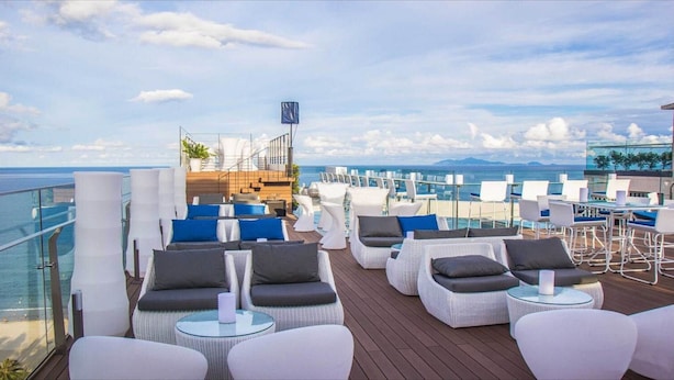A deck with white wicker chairs and tables, a staircase, and a view of the ocean. - Grand View Palace Ha Long Hotel (Hong Gai)