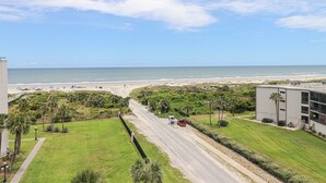 Una strada costiera con vista sulla spiaggia, un'area di parcheggio e un edificio con tetto piatto.