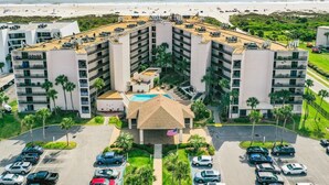 Un hotel a più piani con un cortile centrale, una piscina e un parcheggio.