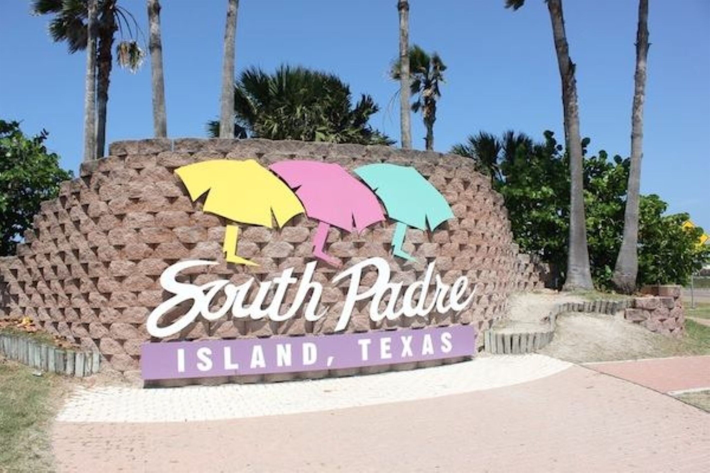 A sign for South Padre Island, Texas, featuring colorful umbrella designs.