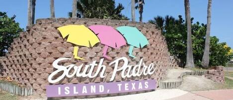 A sign for South Padre Island, Texas, featuring colorful umbrella designs.
