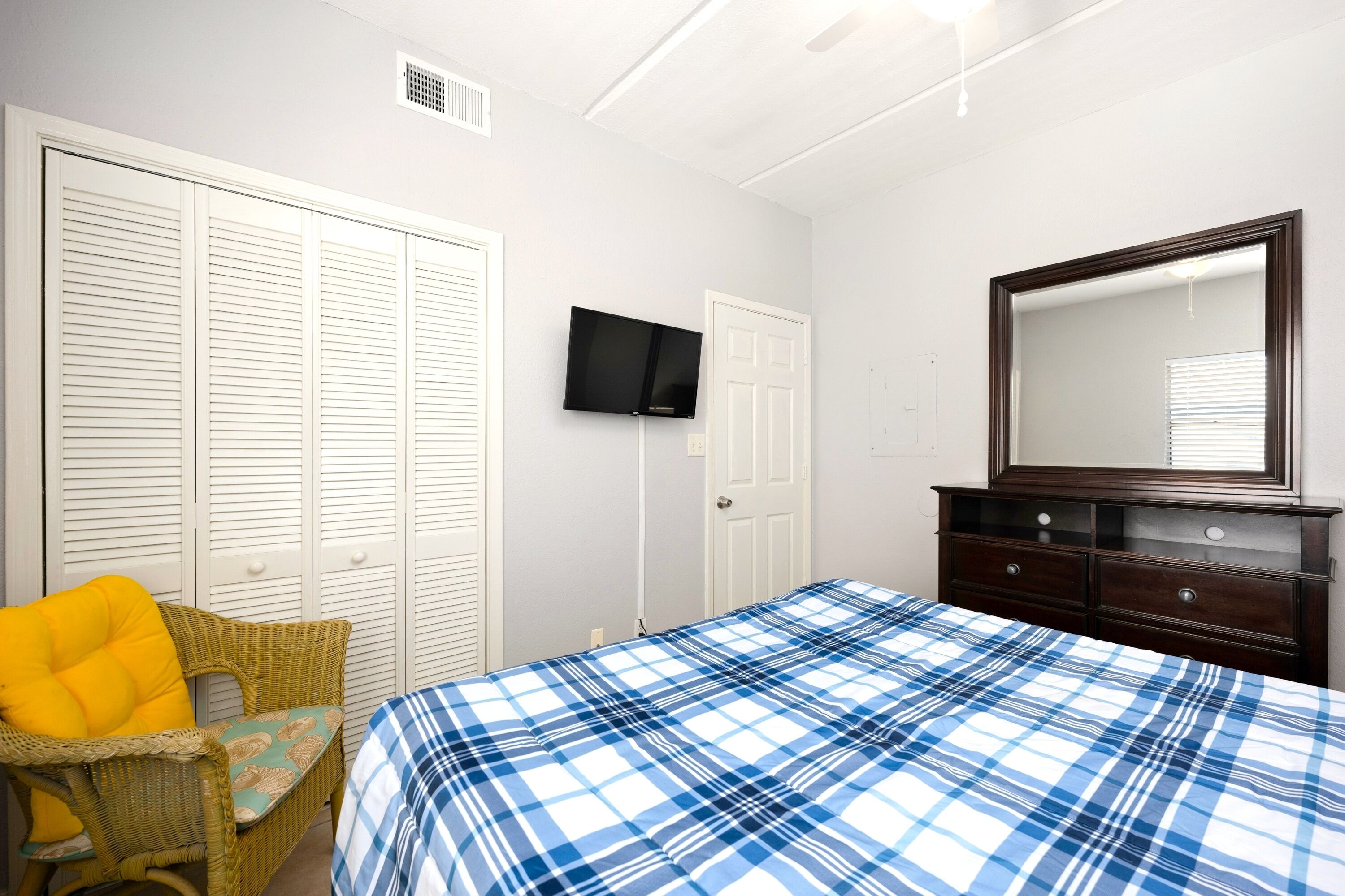 A bedroom with a bed, a television, a dresser, and a chair.