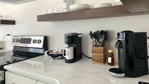 Una cocina moderna con estufa de acero inoxidable, cafetera y máquina Nespresso.