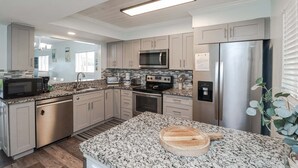Eine moderne Küche mit Edelstahlgeräten, Granit Arbeitsplatten und hellen Holzschränken.
