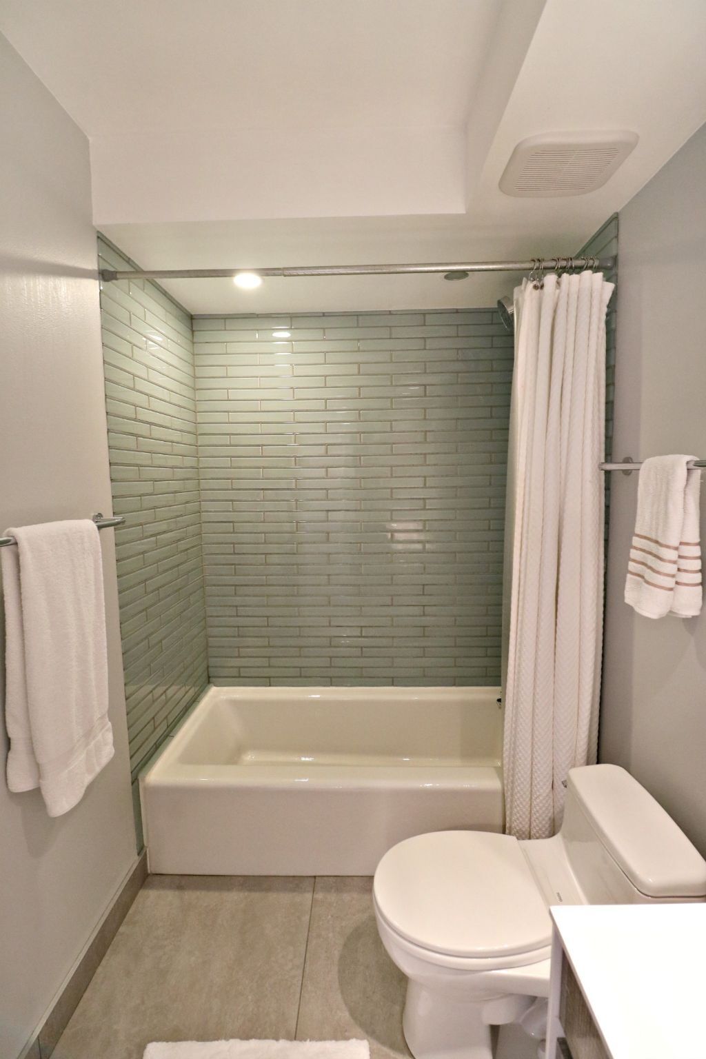 A bathroom with a glass-enclosed shower, a white bathtub, and a toilet.