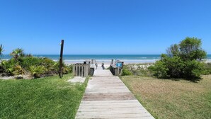 Een houten looppad dat naar een strand leidt, onder heldere luchten.