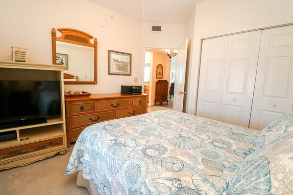 Un dormitorio con cama, cómoda, televisión y una puerta.