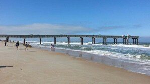 Ein Strand mit einem Steg, der ins Meer führt.