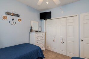 A bedroom with a bed, dresser, and a TV mounted on the wall. - Seaside at Anastasia E302- Renovated Luxury Penthouse Condo (St Augustine)