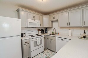 A kitchen with white cabinets, a refrigerator, a microwave, a stove, a sink, and a dishwasher. - Just Steps From the Pool & Beach!! Also has Boat Ramp and Fishing Pier! Trade Winds 51 (St. Augustine)