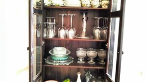 A glass-fronted cabinet with shelves of various glassware, plates, and decorative items. - Haus Nr. 37 (Wunsiedel)