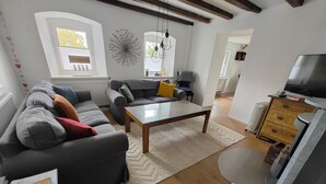 A living room with a sofa, a coffee table, and a TV stand. - Haus Nr. 37 (Wunsiedel)