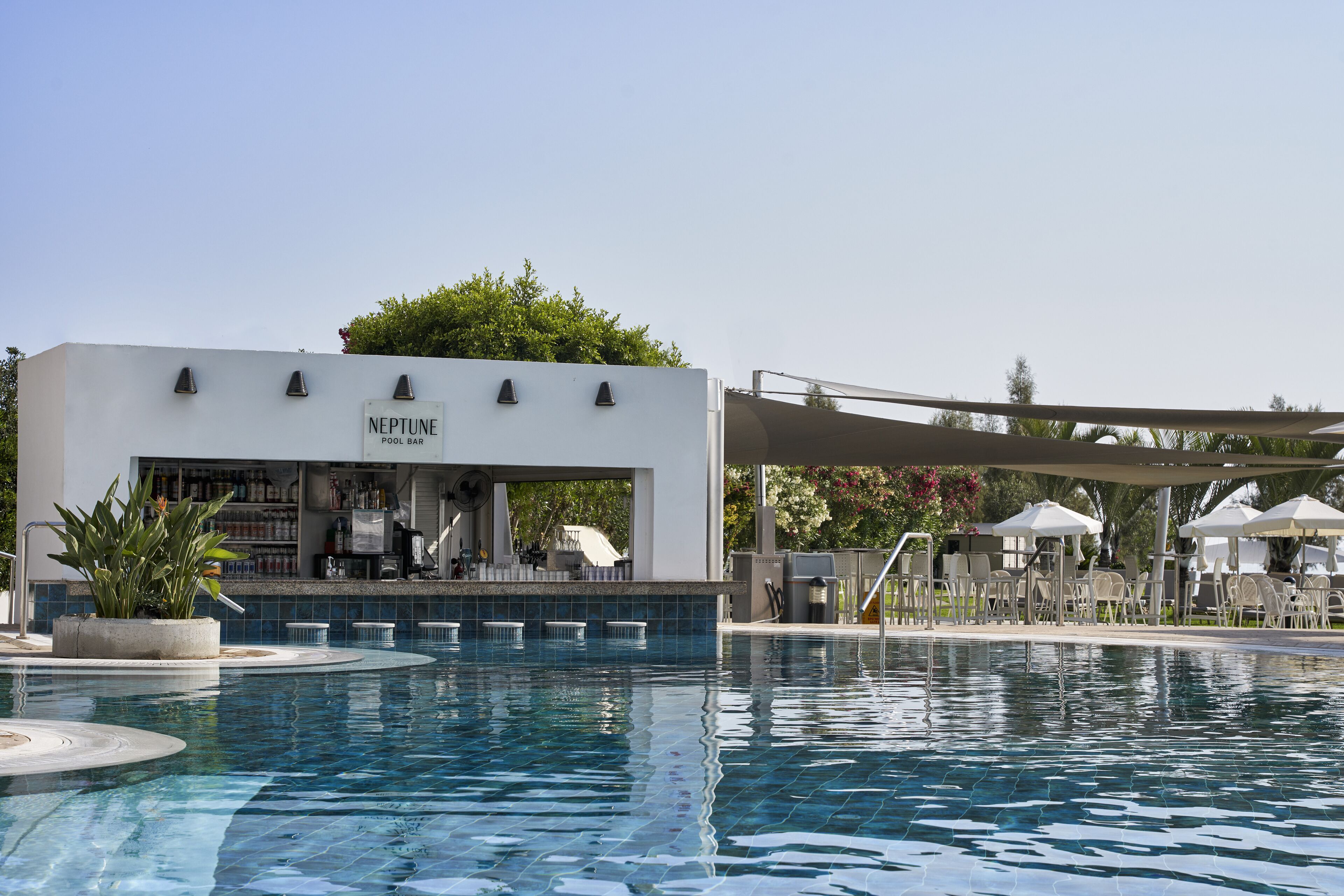 A pool area with a Neptune Pool Bar, lounge chairs, and umbrellas.