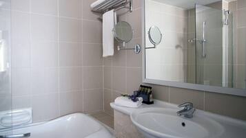 Un baño con bañera, dos lavamanos, un espejo y un perchero para toallas.