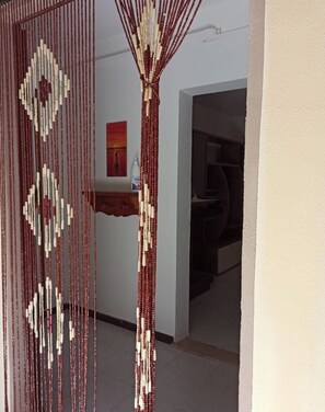 Une porte surmontée d’un rideau décoratif composé de perles.