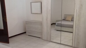 A bedroom with a bed, a dresser, a mirror, and a wardrobe with a mirror. - Fabio&noemi (Domus De Maria)