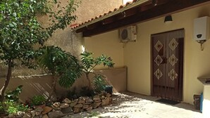 A courtyard with a stone wall, potted plants, and a tiled floor. - Fabio&noemi (Domus De Maria)