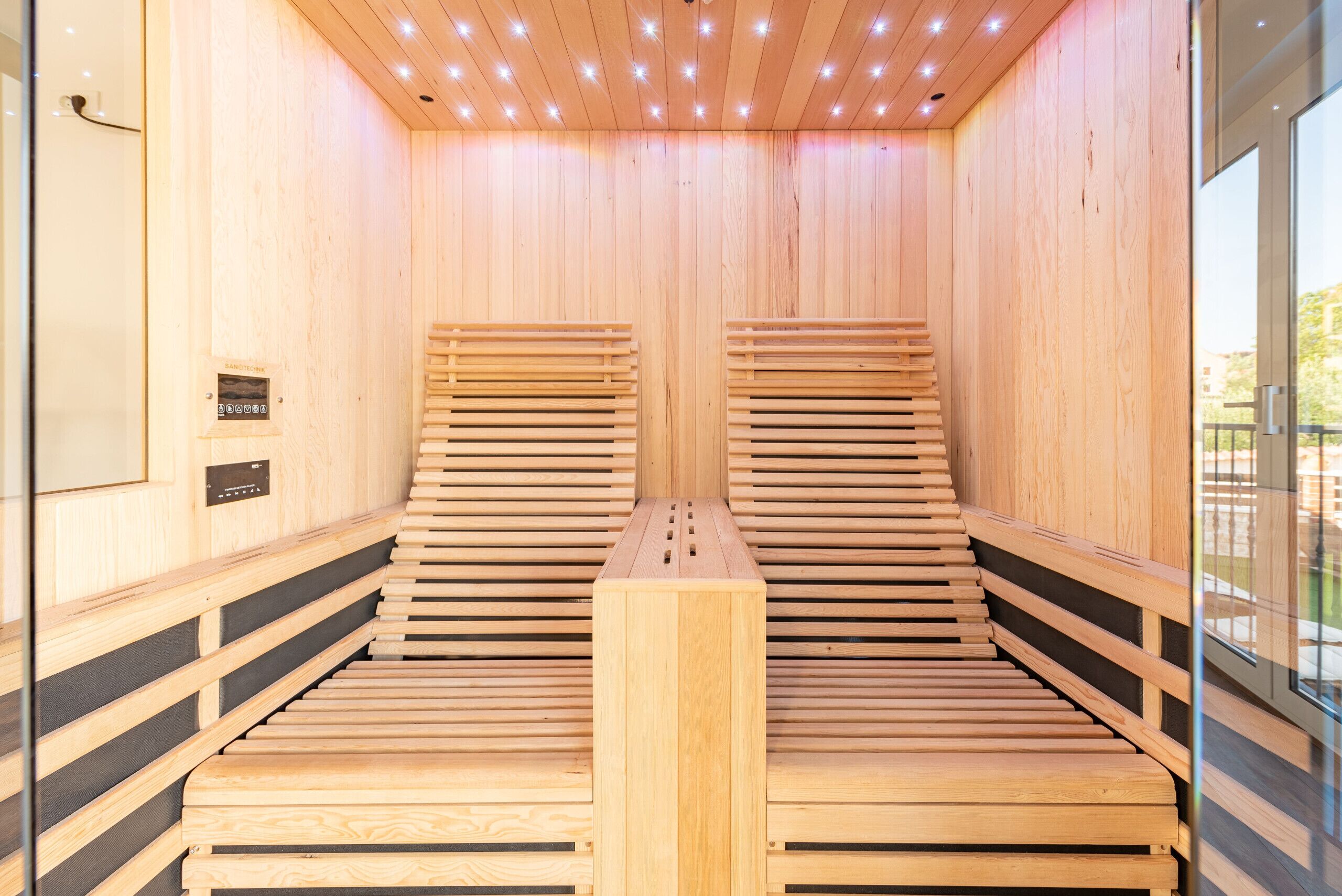 A sauna with wooden benches and a control panel.