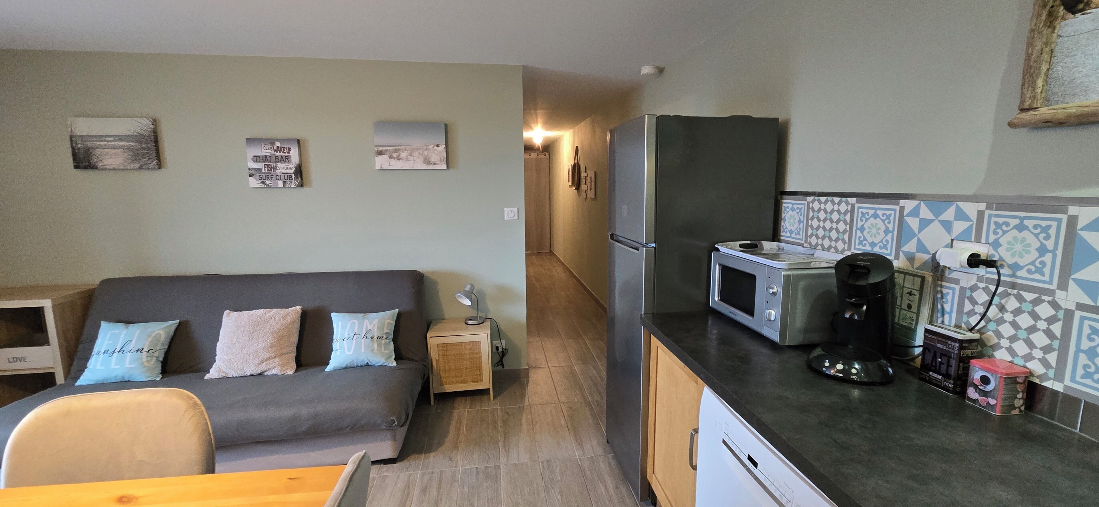 A compact living space with a sofa, a small kitchen area including a microwave and coffee maker, and a dining table.
