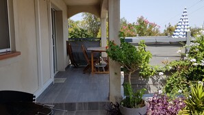 A covered outdoor area with a grill, a table, and chairs, surrounded by potted plants and a view of the sky. - Nice and quiet 3-room apartment with swimming pool Casa Lisa  (Prunelli-di-Fiumorbo)