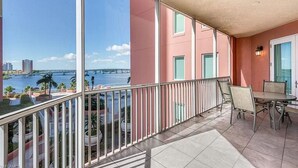 A balcony with a view of a river and bridge, a table with chairs, and a door with a window. - WELCOME to PARADISE! Beautiful sunrise AND sunset views   (Ft. Myers)