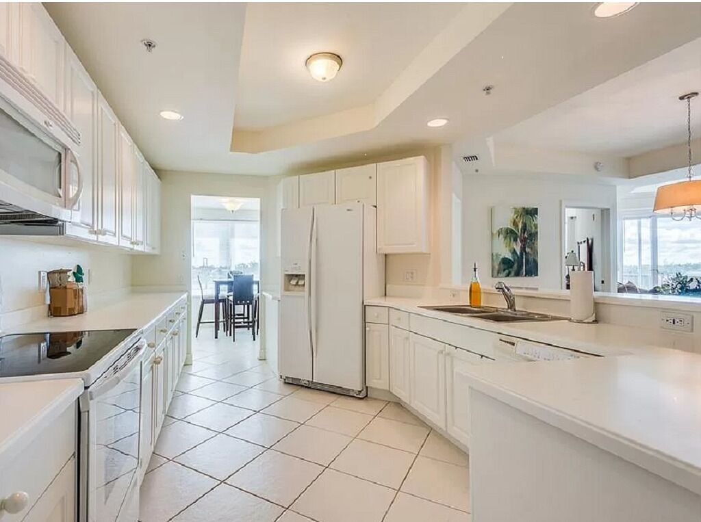 Una cocina moderna con armarios blancos, una isla central y vistas al comedor.