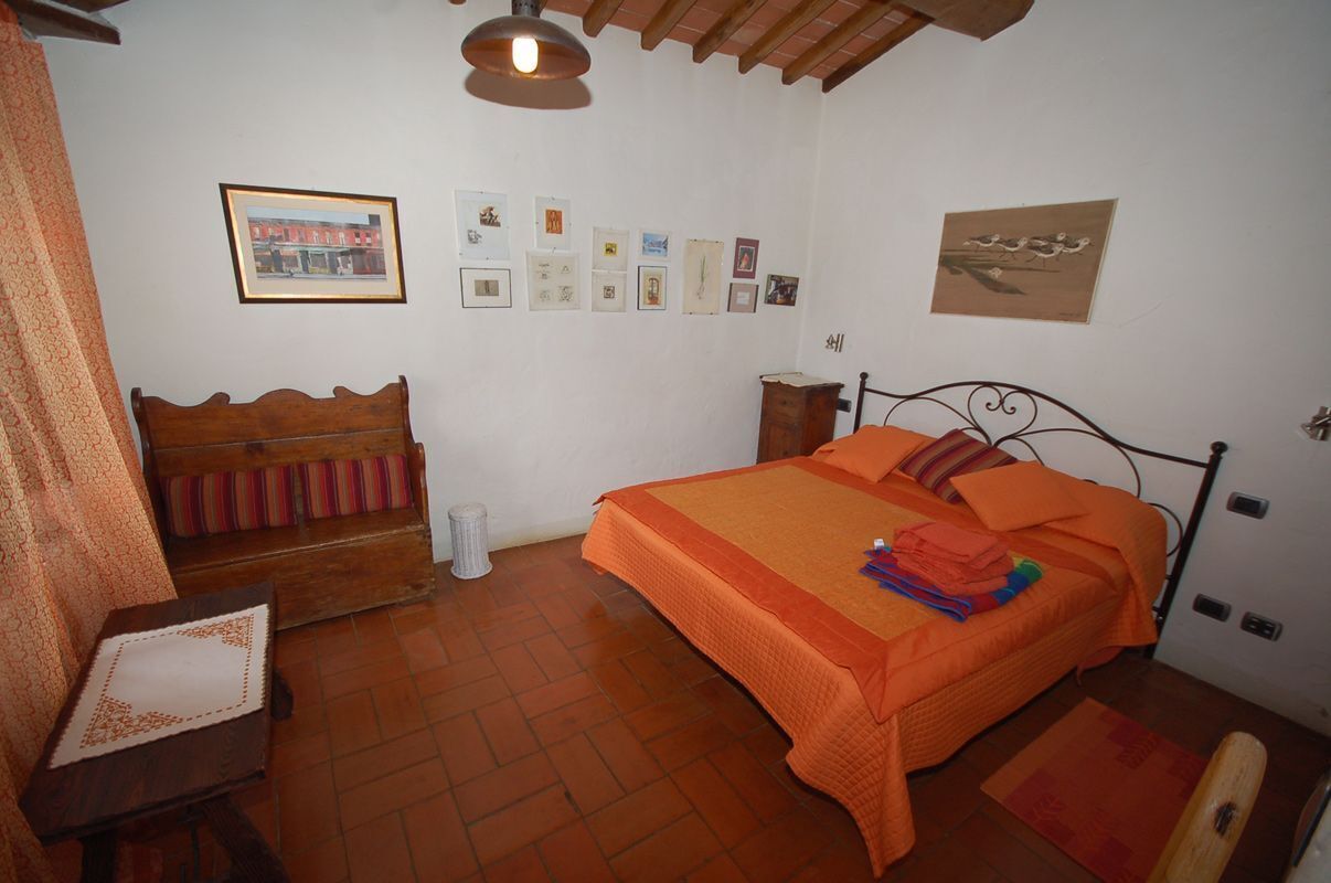 Ein Schlafzimmer mit einem Bett, einer Holzbank, einem kleinen Tisch und einer Wand mit gerahmten Bildern.