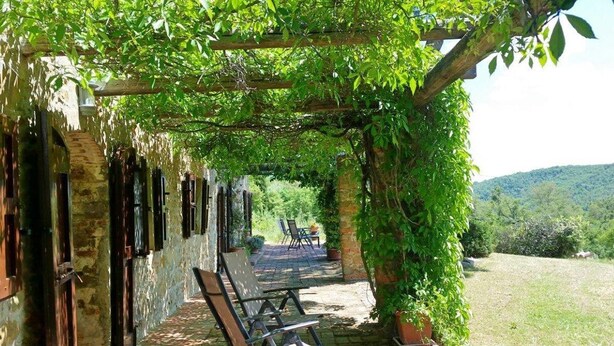Een overdekt terras met stenen muren en een pergola.