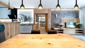 Cocina moderna con detalles de madera, comedor con una mesa grande y un televisor sobre un mueble de madera.