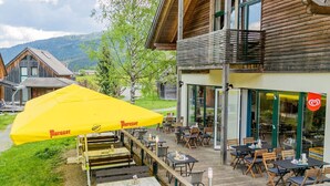 A wooden building with outdoor seating and a yellow umbrella. - Apartment with 1 bedroom (St. Georgen am Kreischberg)