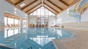 A swimming pool with wooden beams and large windows.