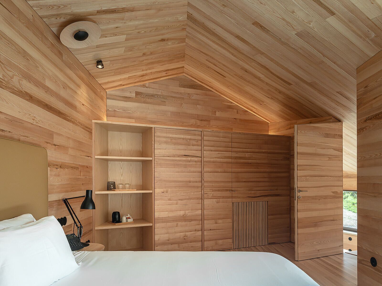 Ein modernes Schlafzimmer mit Holzboden, integrierten Regalen, einem Bett und einer Heizung.