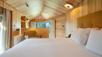 A bedroom with a large bed, a chair, a desk, and a window with curtains.
