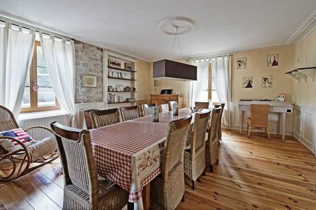 Een eetkamer met een houten tafel, rieten stoelen en een geruit tafelkleed.