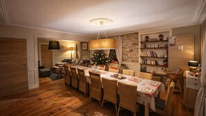A cozy dining area with a long table, wicker chairs, and a Christmas tree. - La Maison de la Cleurie, Gîte Jusqu'à 14 Personnes (Gérardmer)