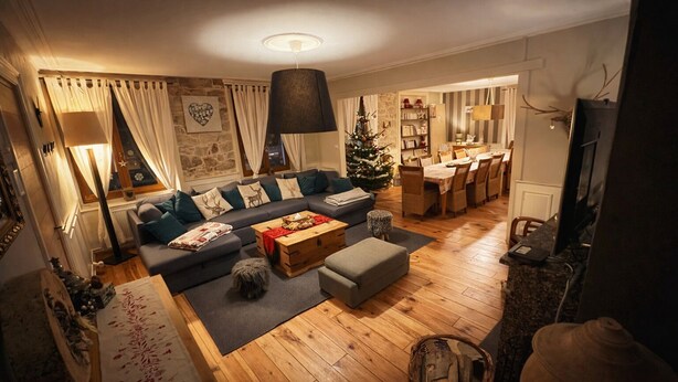 A cozy living room with a sofa, ottoman, and coffee table, a dining area with a table and chairs, and a Christmas tree. - La Maison de la Cleurie, Gîte Jusqu'à 14 Personnes (Gérardmer)