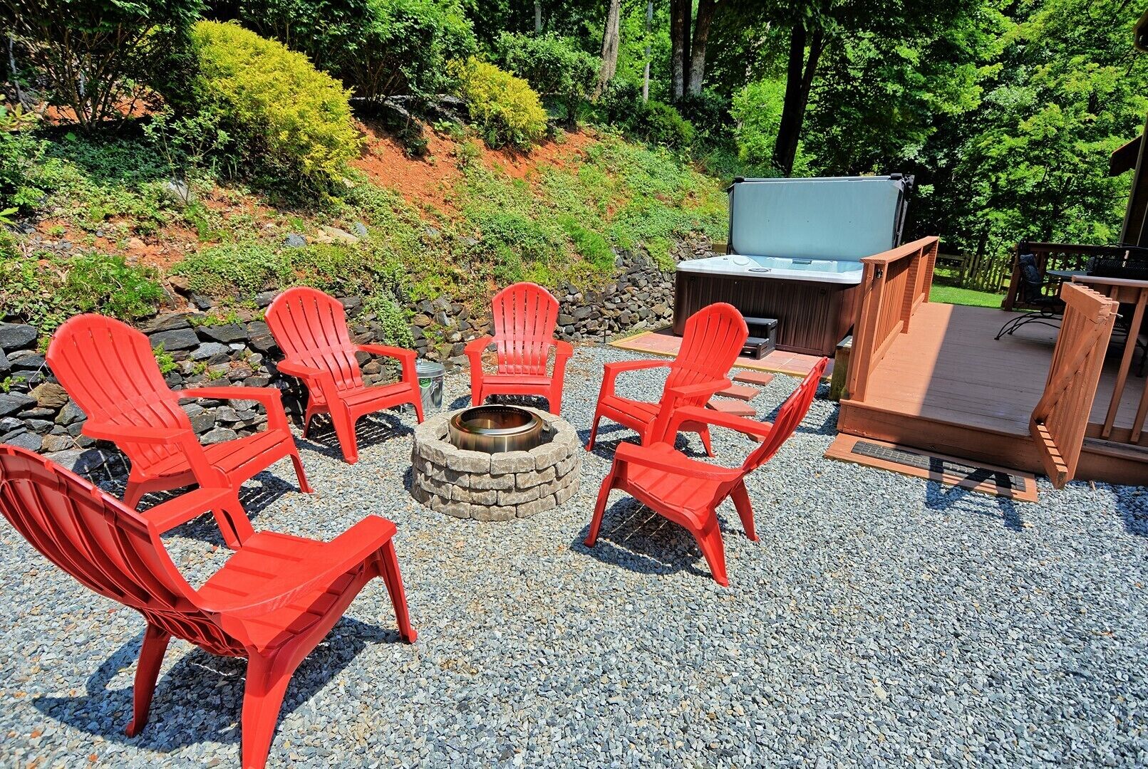 An outdoor seating area with red Adirondack chairs, a fire pit, and a wooden deck.