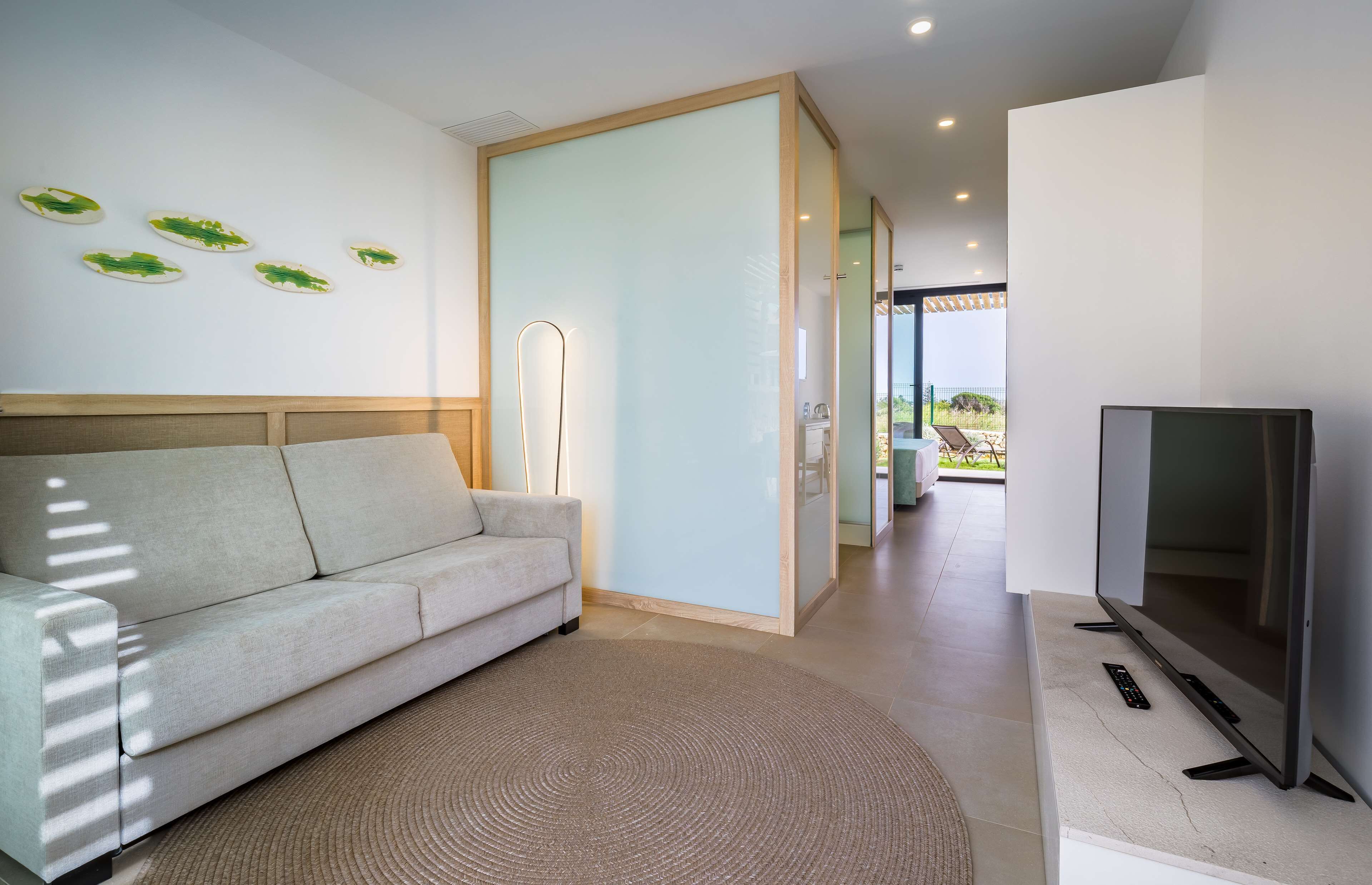 A modern living room with a sofa, a flat-screen TV, and a glass partition.