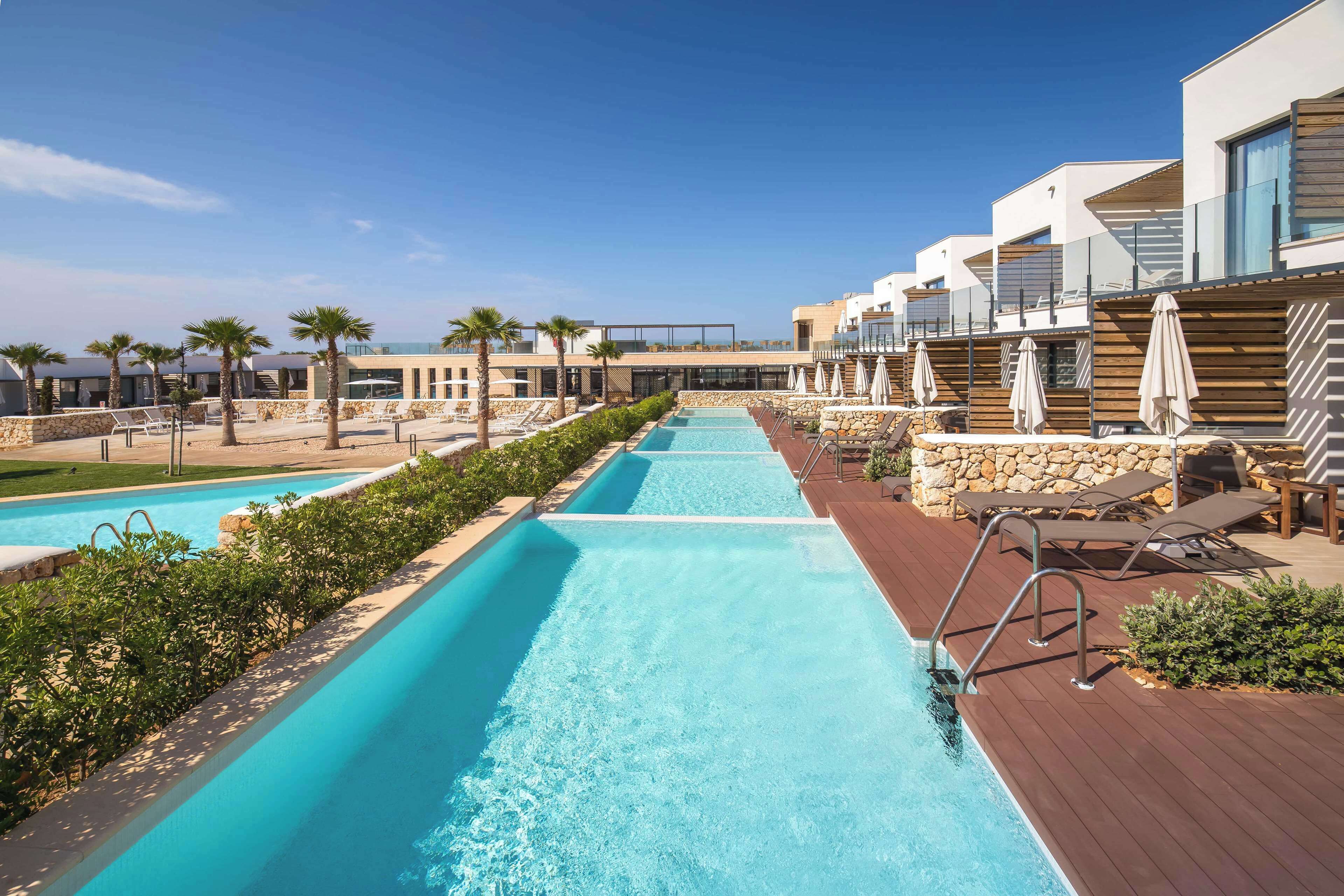 A pool area with multiple swimming pools, lounge chairs, and umbrellas.