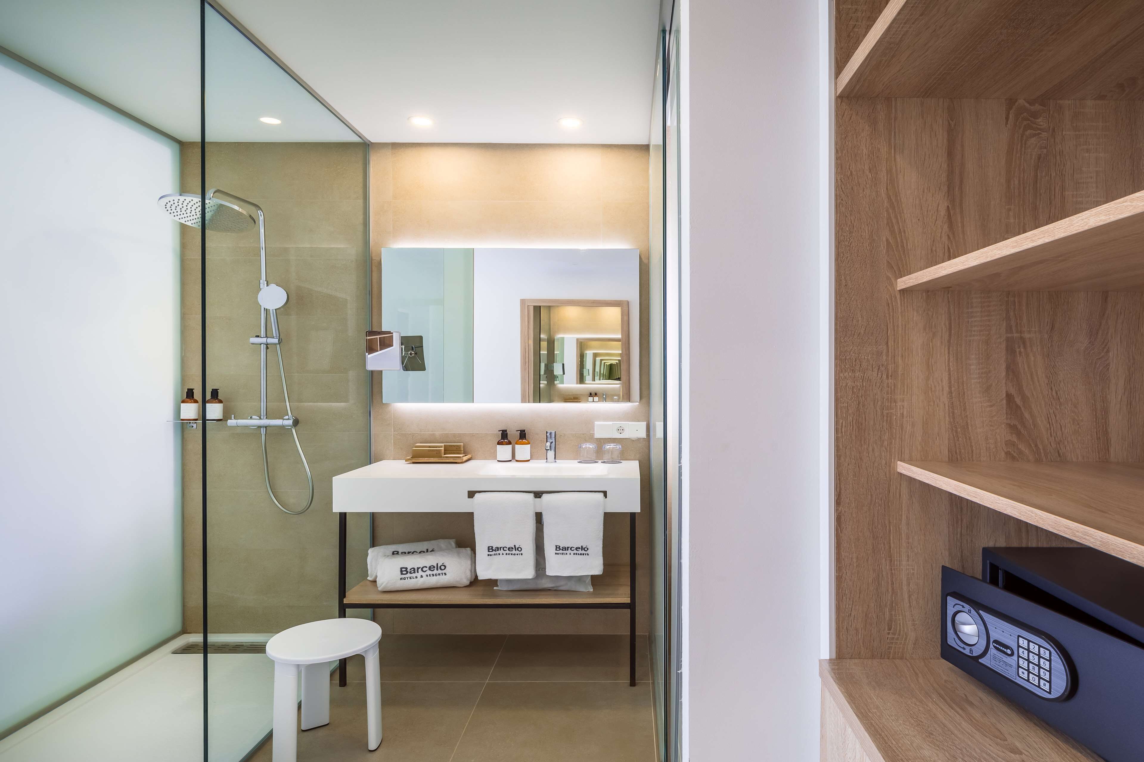 A modern bathroom with a glass shower enclosure, a white sink with a mirror, and a wooden shelf unit.