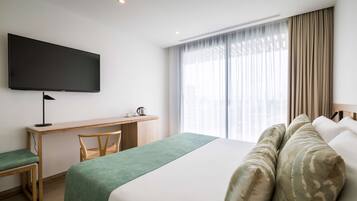 A hotel room with a bed, a desk, a chair, a television, and a window with curtains.